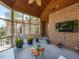 Relaxing screened-in porch with brick wall, mounted TV, and comfortable seating area with custom wood table at 5768 Cavanaugh Dr, Raleigh, NC 27614