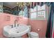 Pink bathroom featuring a pedestal sink, tiled walls, and vintage fixtures at 609 W Main St, Benson, NC 27504
