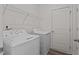 Laundry room with modern washer and dryer, storage shelves, and wood-look floors at 7385 Pilatus Ave, Spring Hope, NC 27882