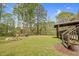 View of a spacious, green backyard with a fire pit and seating, accessible from a wooden deck at 93 Clifton Pond Rd, Louisburg, NC 27549