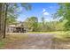 Property with spacious driveway and charming curb appeal, enhanced by lush landscaping, creating a welcoming atmosphere at 93 Clifton Pond Rd, Louisburg, NC 27549