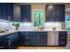Modern kitchen features navy cabinets, gold hardware, white countertops and backsplash, plus stainless steel dishwasher at 103 Windhover Dr, Chapel Hill, NC 27514
