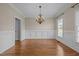 An empty dining room with chair railing and hardwood flooring under an elegant chandelier at 104 Dallavia Ct, Morrisville, NC 27560
