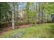 Backyard with a wooden fence, mature trees, and a glimpse of the house in the background at 109 Homegate Cir, Apex, NC 27502