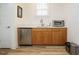 Well-lit kitchenette features wood cabinets, a stainless steel sink, a mini-fridge, and sleek countertops at 110 Streamside Dr, Sanford, NC 27330