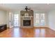 Bright living room featuring a brick fireplace, hardwood floors, ceiling fan and French doors to a deck at 111 Fox View Pl, Cary, NC 27511