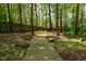 Landscaped backyard with a wooden bridge, mature trees, and a peaceful wooded area at 113 Glenmore Rd, Chapel Hill, NC 27516