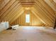 Spacious unfinished attic with exposed beams, plywood flooring, and natural light from a window at 113 Tower Ridge Ln, Sanford, NC 27330