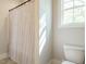 Clean bathroom with a toilet, shower with striped curtain and a window, providing natural light and ventilation at 113 Tower Ridge Ln, Sanford, NC 27330