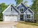 Charming blue home featuring stone accents, an attached garage, and a well-manicured lawn at 113 Tower Ridge Ln, Sanford, NC 27330