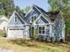 Charming blue home featuring stone accents, an attached garage, and a well-manicured lawn at 113 Tower Ridge Ln, Sanford, NC 27330