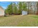 Large backyard with a storage shed, swing set, firepit, and a black metal fence at 114 Carriage Hill Dr, Stem, NC 27581