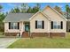 Charming single-story home with light yellow siding, black shutters, and well-manicured lawn at 114 Carriage Hill Dr, Stem, NC 27581