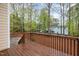 View from wooden deck of the backyard with mature trees and a stone patio area at 120 Cypress View Way, Apex, NC 27502
