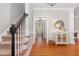 Hallway with hardwood floors, staircase with a black handrail, and decorative table under a decorative mirror at 120 Cypress View Way, Apex, NC 27502