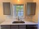 Close-up of a kitchen sink with gray cabinets, white marble countertops, and stainless steel fixtures at 1204 Amberstone Dr, Knightdale, NC 27545
