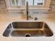 Close up of a modern stainless steel kitchen sink with marble backsplash and countertop at 1204 Amberstone Dr, Knightdale, NC 27545