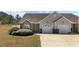 Charming home featuring a brick facade, grey siding, well-kept landscaping, and a two-car garage at 123 Ariel St, Lillington, NC 27546