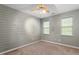 Comfortable bedroom features a ceiling fan and a stylish accent wall with natural light from the windows at 147 W Alex Dr, Clayton, NC 27520
