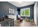 Bedroom with hardwood floors, crib, dresser, glider, and large window at 1500 Antioch Rd, Rocky Mount, NC 27801