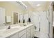 Bright bathroom featuring double sinks, a large mirror with vanity lighting, and a glass-enclosed shower at 1515 Poets Glade Dr, Apex, NC 27523