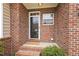 Welcoming brick front porch with a storm door entry, decorative window, and charming landscaping at 1515 Poets Glade Dr, Apex, NC 27523
