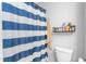 Cozy bathroom featuring a blue and white striped shower curtain and storage shelf at 1725 Langlais Dr, Graham, NC 27253