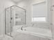 Bathroom showcasing a glass enclosed shower and a soaking tub with marble tile surround at 173 Hawk Point Rd, Chapel Hill, NC 27516