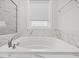 Bathroom featuring soaking tub with marble tile surround and a window providing natural light at 173 Hawk Point Rd, Chapel Hill, NC 27516
