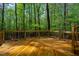 Spacious wooden deck featuring decorative wood railings overlooking lush greenery and mature trees for outdoor living at 18 Green Ridge Ln, Pittsboro, NC 27312