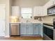 Well-lit kitchen featuring stainless steel appliances and two-tone cabinets under a window at 202 Providence Hall Dr, Sanford, NC 27330