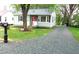 Charming single-story home features a gravel driveway, manicured lawn, and a cozy front porch with a red door at 2117 Wrenn St, Burlington, NC 27215