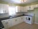 Well-lit kitchen featuring white cabinets, black countertops, tile backsplash, and a tile floor at 2117 Wrenn St, Burlington, NC 27215