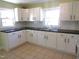 Well-lit kitchen featuring white cabinets, black countertops, tile backsplash, and a tile floor at 2117 Wrenn St, Burlington, NC 27215