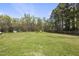 Spacious backyard with lush green grass and mature trees, ideal for outdoor activities at 230 Bradley Dr, Benson, NC 27504