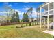 A spacious backyard with green grass, privacy fence, mature trees, and a covered porch at 2321 Swansea Ln, Apex, NC 27502