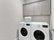 Modern laundry room with white washer and dryer, gray cabinets, and tile flooring for easy maintenance at 2321 Swansea Ln, Apex, NC 27502