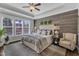 Serene main bedroom with a wood-accent wall, tray ceiling, and large windows for ample natural light at 2321 Swansea Ln, Apex, NC 27502