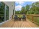 View of a wood deck with two chairs and a small table with a view of trees and grass at 25 Granite Falls Way, Youngsville, NC 27596