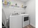 Efficient laundry room with modern, white appliances and overhead shelving for organized storage at 254 W Odell Ln, Zebulon, NC 27597