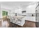 Modern white kitchen features a large island with seating, granite countertops, stainless steel appliances, and an open dining area at 2613 Beckwith Rd, Apex, NC 27523