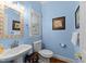 Charming powder room featuring a pedestal sink, decorative mirror, and bright blue painted walls at 2613 Hiking Trl, Raleigh, NC 27615