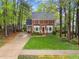Charming brick home featuring a well-manicured lawn, complemented by lush trees and vibrant landscaping at 2613 Hiking Trl, Raleigh, NC 27615