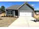 Picture of a new home featuring an attached two-car garage, gray siding, a gray roof, and a well-lit driveway at 288 Olivia Crossing Ct # 10, Four Oaks, NC 27524