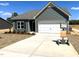 Exterior view of a new construction gray home featuring a two-car garage and a well-lit driveway on a sunny day at 288 Olivia Crossing Ct # 10, Four Oaks, NC 27524