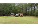 Wide backyard with plentiful foliage, a trailer, storage shed and two pickup trucks at 300 E Vance St, Zebulon, NC 27597