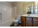 Bathroom with a shower-tub combo, oak vanity, and a mirror reflecting natural light from the window at 300 Nc 54 Highway # E2, Carrboro, NC 27510