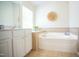 Bathroom featuring a white vanity with a large mirror, a soaking tub, and neutral tile flooring at 3303 Silver Star Dr, Durham, NC 27713