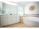 Bathroom featuring a white vanity with a large mirror, a soaking tub, and neutral tile flooring at 3303 Silver Star Dr, Durham, NC 27713