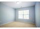 Empty bedroom with neutral carpet, light blue walls, and a window allowing natural light at 3303 Silver Star Dr, Durham, NC 27713